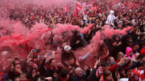 Reuters A large crowd of Liverpool fans, some with smoke flares, during the victory parade on 26 May 2025.