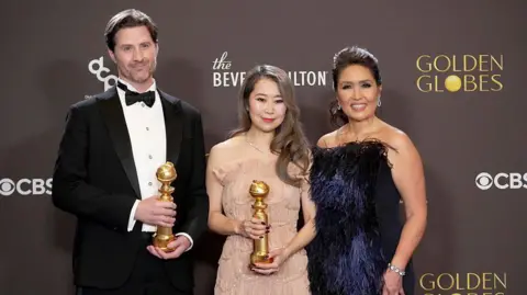 Getty Images Chris Appelhans, Maggie Kang e Michelle Wong, vincitori del premio come miglior film d'animazione per "Cacciatori di demoni KPop," posa nella sala stampa dell'83a edizione dei Golden Globe Awards al Beverly Hilton l'11 gennaio 2026 a Beverly Hills, California.