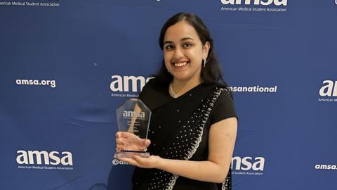 Naabil Khan holding her award in both hands