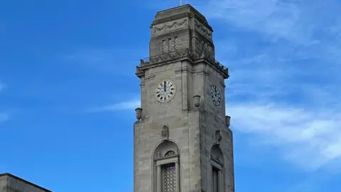 Barnsley Town Hall's clock tower: a tall, slim building in white stone with a clock face displayed on all four sides of the tower
