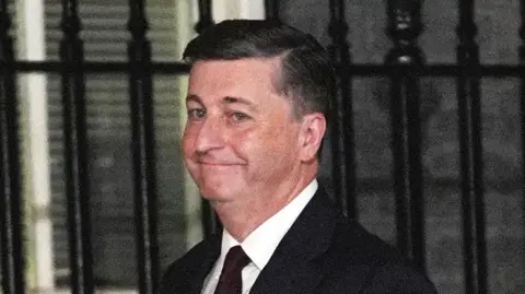 Douglas Alexander has short grey hair and wears a dark suit