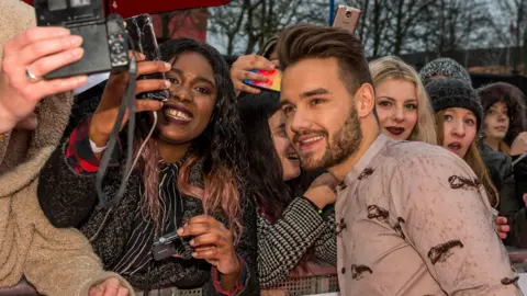 BBC A man takes photos with fans at an awards ceremony