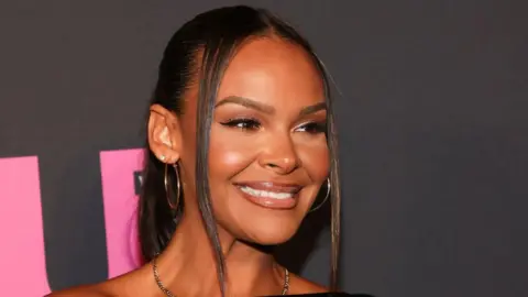 Samantha Mumba has long, dark hair and brown eyes and is smiling at an awards ceremony 