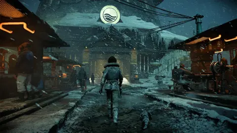 Ubisoft A screenshot from the Star Wars Outlaws game, showing a character walking towards a big building in cold snowy conditions, with wooden taverns either side.