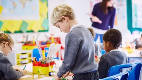 Children in grey uniforms working in a colourful classroom