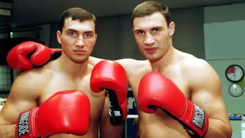 Getty Images Vitali and Vladimir Klitschko wearing boxing gloves, pictured in 1998