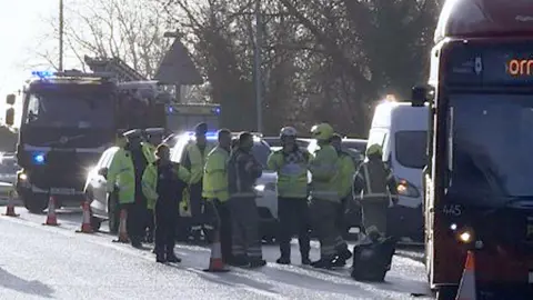 BBC A picture of the bus and emergency services personnel, including a fire engine, on the slip road.