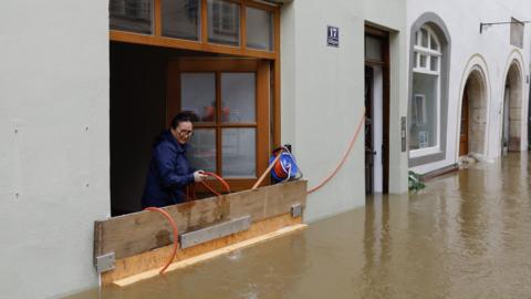  A woman tries to pump water with a hose out of her house in a flooded street and houses in the center of Passau in Bavaria, southern Germany, on June 4, 2024