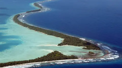 Getty Images A very narrow stretch of land is surrounded by shallow turquoise water.