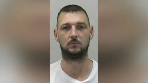 Northumbria Police Mugshot of Michael Webb. He has a scruffy black beard and short black hair.