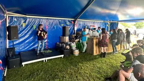 Audience watches singer perform in a tent