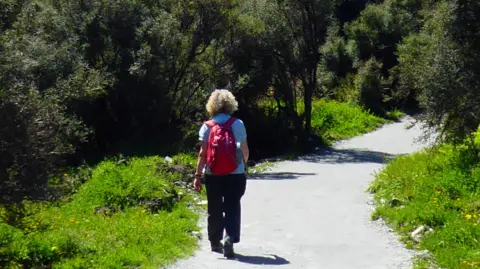 Family handout Alison on a walking trail with her back to the camera she is wearing a red backpack