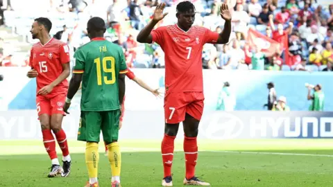 Getty Images Breel Embolo of Switzerland, wearing a red shirt with the number seven on it, raises his arms after scoring against Cameroon, his country of birth, in the 2022 World Cup