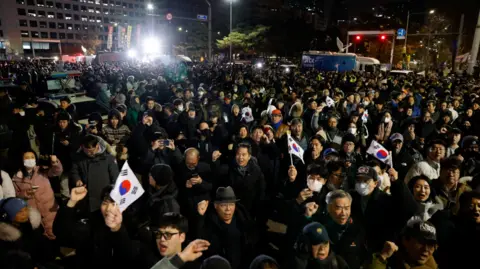 Reuters A crowd of protesters outside parliament chant 'No Martial law' and hold up the South Korean flag.