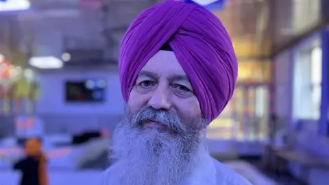 Jagjit Singh Kular looking at the camera with a purple turban on and a long white beard.