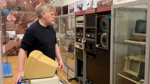 Curator Brendan Carr places one of the DEC computers from the 1970s in a display within Reading Museum.