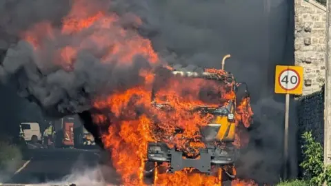 A gritter lorry completely engulfed in flames.