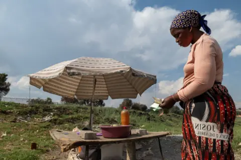 Getty Images A Street Vendor menghitung uang kertas Rand di sebuah kios jagung dan kacang di Johannesburg, Afrika Selatan, pada 26 Oktober 2024