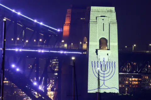 An image of a menorah is projected onto the pylons of the Sydney Harbor Bridge during New Year's Eve celebrations on December 31, 2025 in Sydney, Australia.