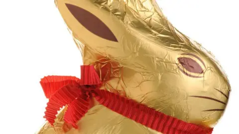 Getty Images A close-up of a Lindt gold bunny chocolate rabbit. It has gold foil wrapping and a red bow around its neck.