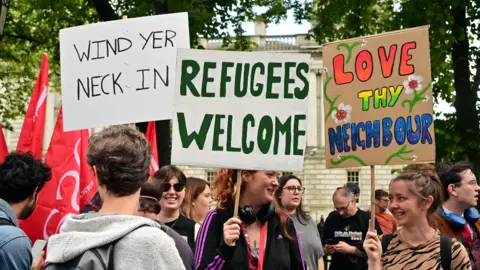 Pacemaker Placards at an anti racism rally in Belfast saying Refugees welcome and Wind Your Neck In