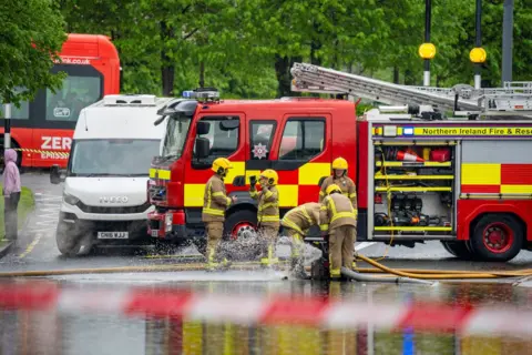 Aodhán Roberts A fire engine with four fire fighters standing in front of it 