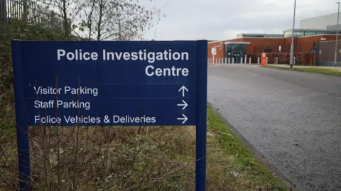 Shaun Whitmore/BBC The outside of Aylsham Police Investigation Centre. On the left in the foreground is a blue sign directly people towards the building and parking. In the background is the centre.