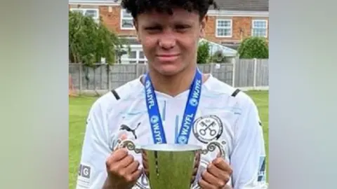 West Midlands Police Harleigh Hepworth in a football kit holding a trophy