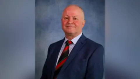 Caerphilly council Sean Morgan in a council portrait, with a striped tie, a white shirt and a blue jacket.