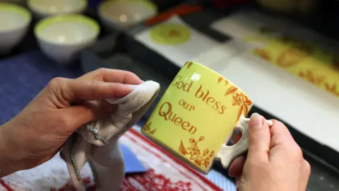 STOKE, ENGLAND - MARCH 27: Lithographer, Karen Heath, works on a Burleigh Diamond Jubilee mug at Middleport Pottery, on March 27, 2012 in Stoke-on-Trent, England. The historic Middleport Pottery - Britain's last working Victorian pottery and home of Burleighware