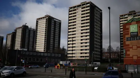 EPA A woman walks in front of the Seven Sisters residential tower blocks ahead.