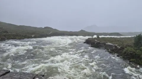 Skye Mountain Rescue Team A fast flowing section of water under a gun metal grey sky.