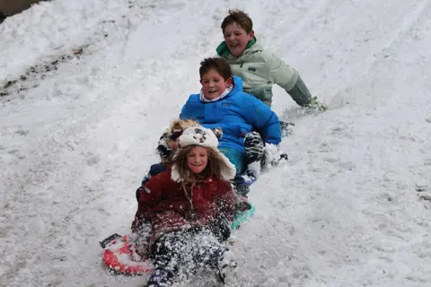 Getty Images Vier kinderen sleeën in de sneeuw in Brooklyn na een nachtelijke storm