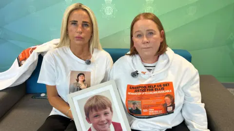 BBC Ellis's mum Carolyn Cox (left) is a blond woman. She sits next to Ellis's auntie Julie O'Toole (right) who has ginger hair. Both wear hoodies and t-shirts showing Ellis's face and hold a photograph of Ellis as a child.