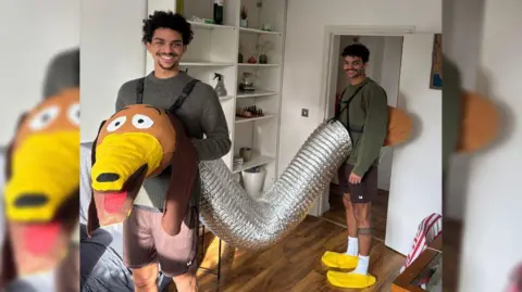 Brighton Half Marathon Two men stood in a living room dressed as Slinky Dog. 