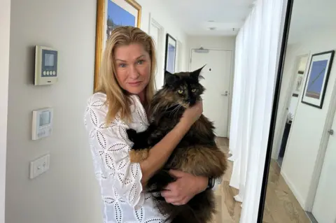 Margo Neas holds her cat Mittens in corridor of her home in Melbourne. Photo: 22 January 2025