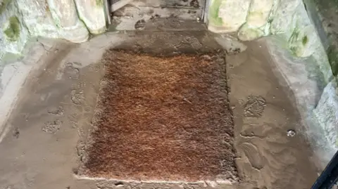 Rich Townend A mat in front of the church with mud all around it 