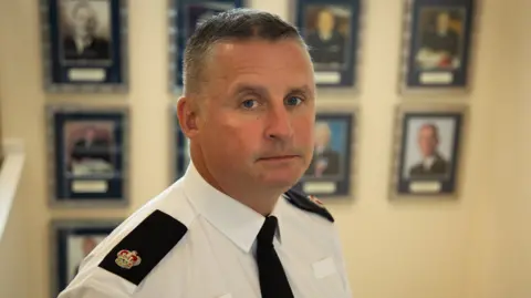 A middle-aged policeman, Det Sgt Gareth Morgan, looks at the camera in his uniform