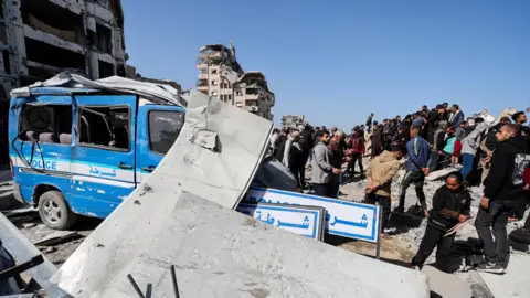 Reuters A police mini van with rubble on top of it, surrounded by several people