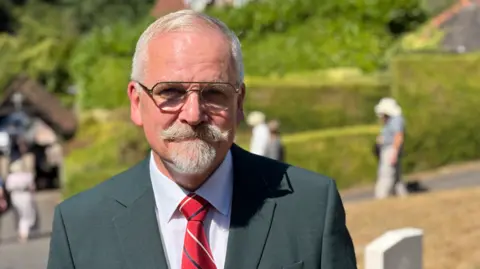 A man wearing a suit and glasses is looking at the camera