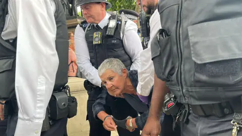 A woman being handcuffed and dragged away by police at protests in support of Palestine Action 