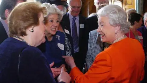 Getty Images Patricia Routledge, Betty Boothroyd, both wearing navy blue, met Queen Elizabeth II in 2006 and are seen talking in a reception room at Buckingham Palace. Other guests are visible in the background at what was a "Serving Beyond Sixty" reception for people over the age of sixty making a significant contribution to national life.