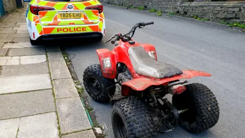 A red quad park parked behind a police car 