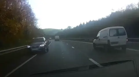 Operation Snap A dashcam video shows a black audi driving the wrong way down the inside of the A38 towards oncoming traffic. A white van is driving in the outside lane.