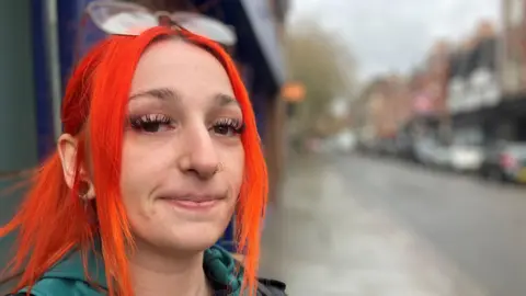 Dharma Mundell with bright orange hair and glasses on the top of her head