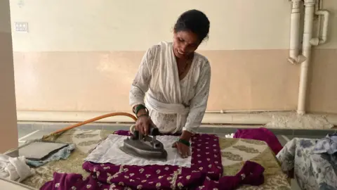 Sarita Devi, who irons clothes for a living, says she can’t afford to return to her hometown despite the deteriorating air quality in Delhi