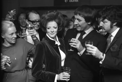 Mirrorpix via Getty Images Maggie Smith, with her husband Robert Stevens and friends celebrating her Oscar winning award with a small party at the Stalls Bar in The Old Vic on the night of her first performance. 8th April 1970.