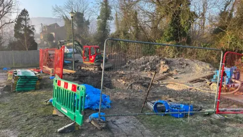 A building site with mounds of dirt and red and green fences