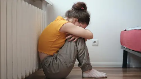 Getty Images Sad lonely teen sitting on floor near smartphone and crying, feeling depressed. 