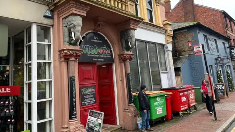 Phil Harrison/BBC The outside of a snooker club. There are two people walking past the building. 